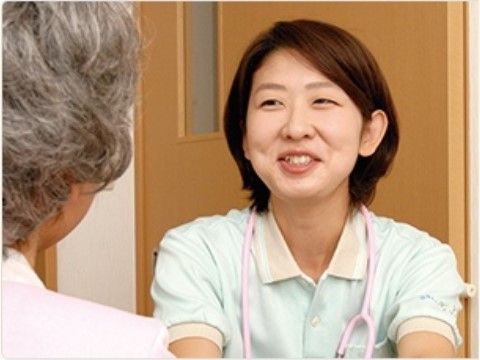笑顔の女性スタッフと座って会話をしている、入居者の女性