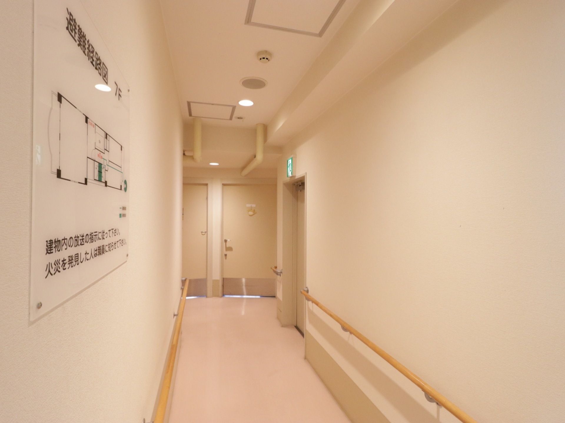 通路の幅は広く、両脇に手すりがついている。壁は白く、照明も明るく開放的。大きく見やすい避難経路図がある。