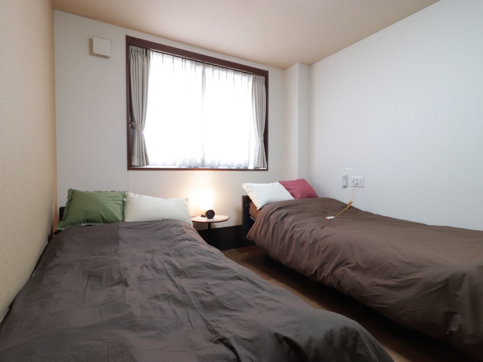 ベッドが二つ入っている二人部屋の居室。中央の枕元には、ランプの置かれた小型のテーブルが配置されている。