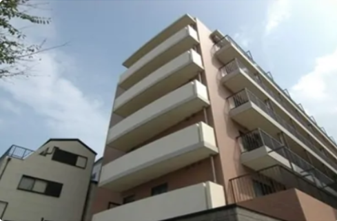 建物の前に駐車場が広がっている、白壁の三階建ての施設外観
