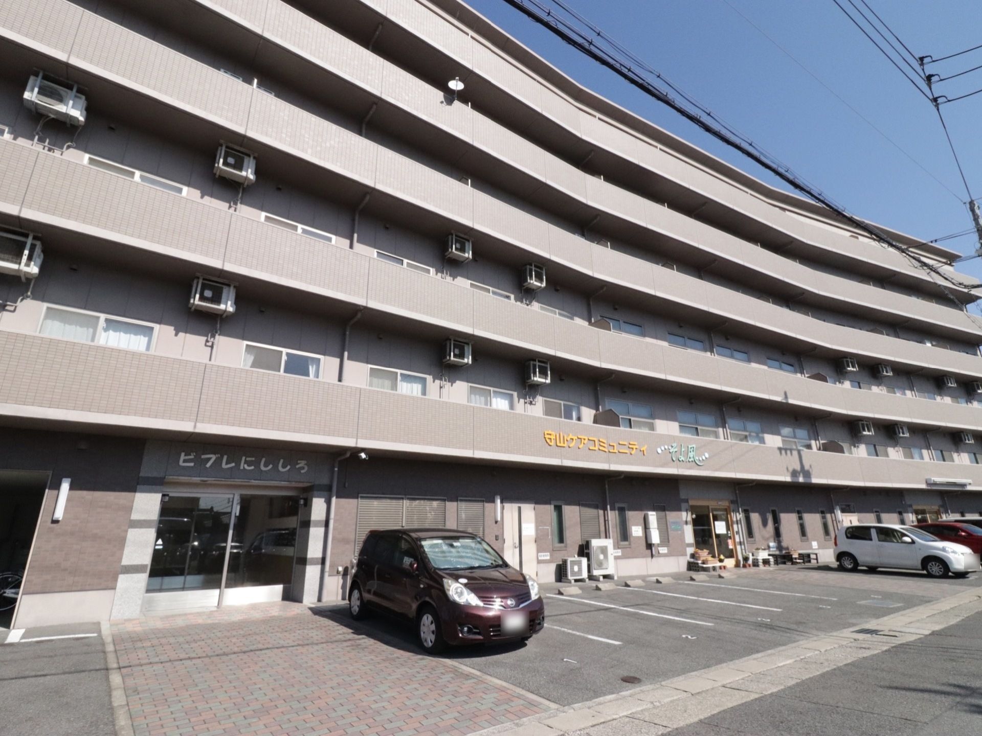 建物に沿って駐車するスペースが並んでいる。道路に面していて駐車スペースは広いため、バックでの駐車も行いやすい。