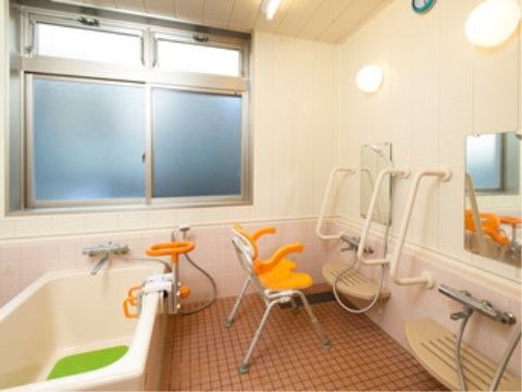 浴室の洗い場には入浴用の椅子が設置してあり、入居者様は楽な姿勢で身体を洗うことができる。壁には手すりが複数ついている。