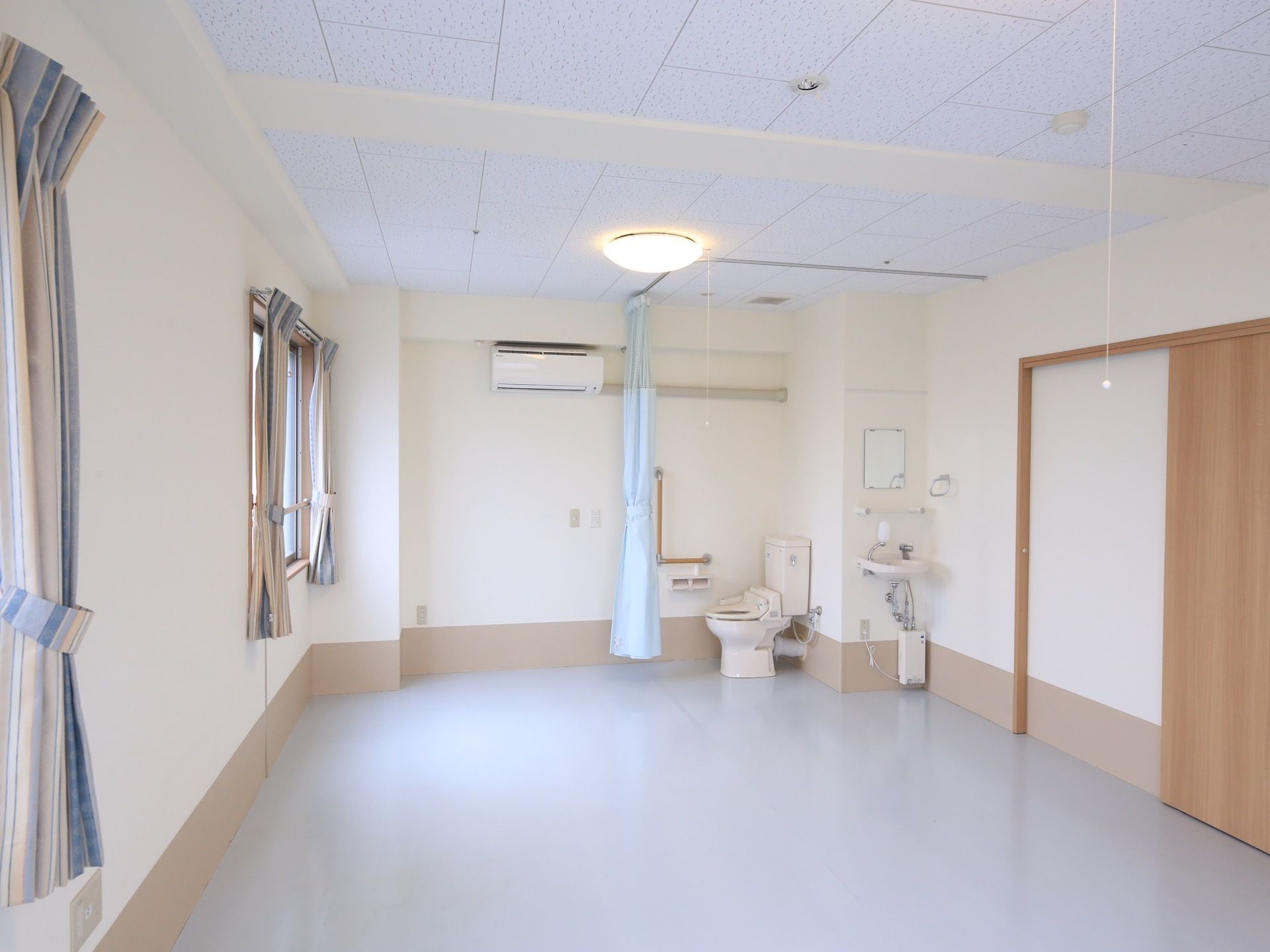 洗面台やトイレ、エアコンが完備された居室である。２箇所に窓が設けられている。トイレの扉には、カーテンが採用されている。