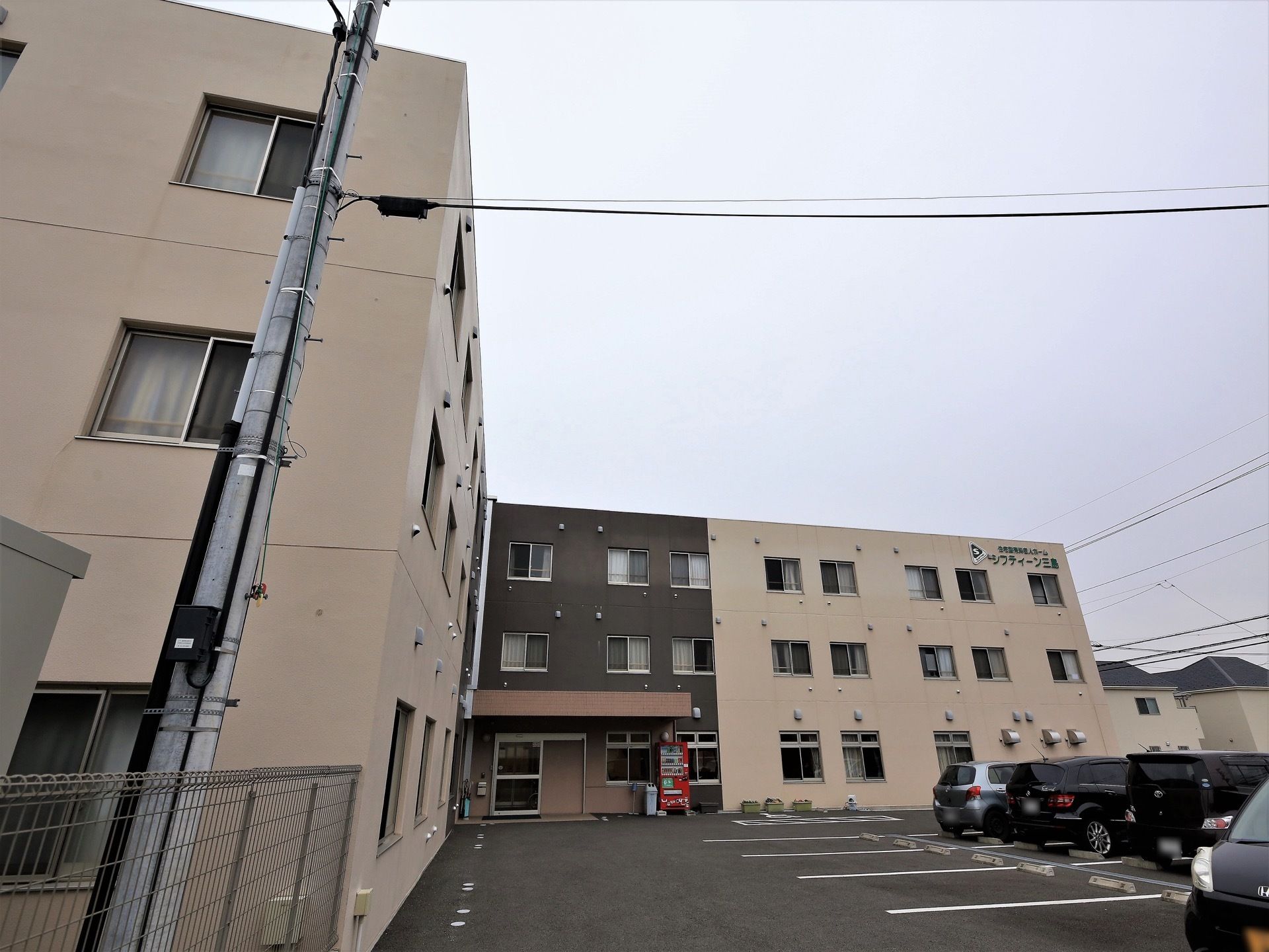 施設は鉄骨造りの３階建て建物である。エントランスにひさしが設置されており、広い駐車場が建物前に設けられている。