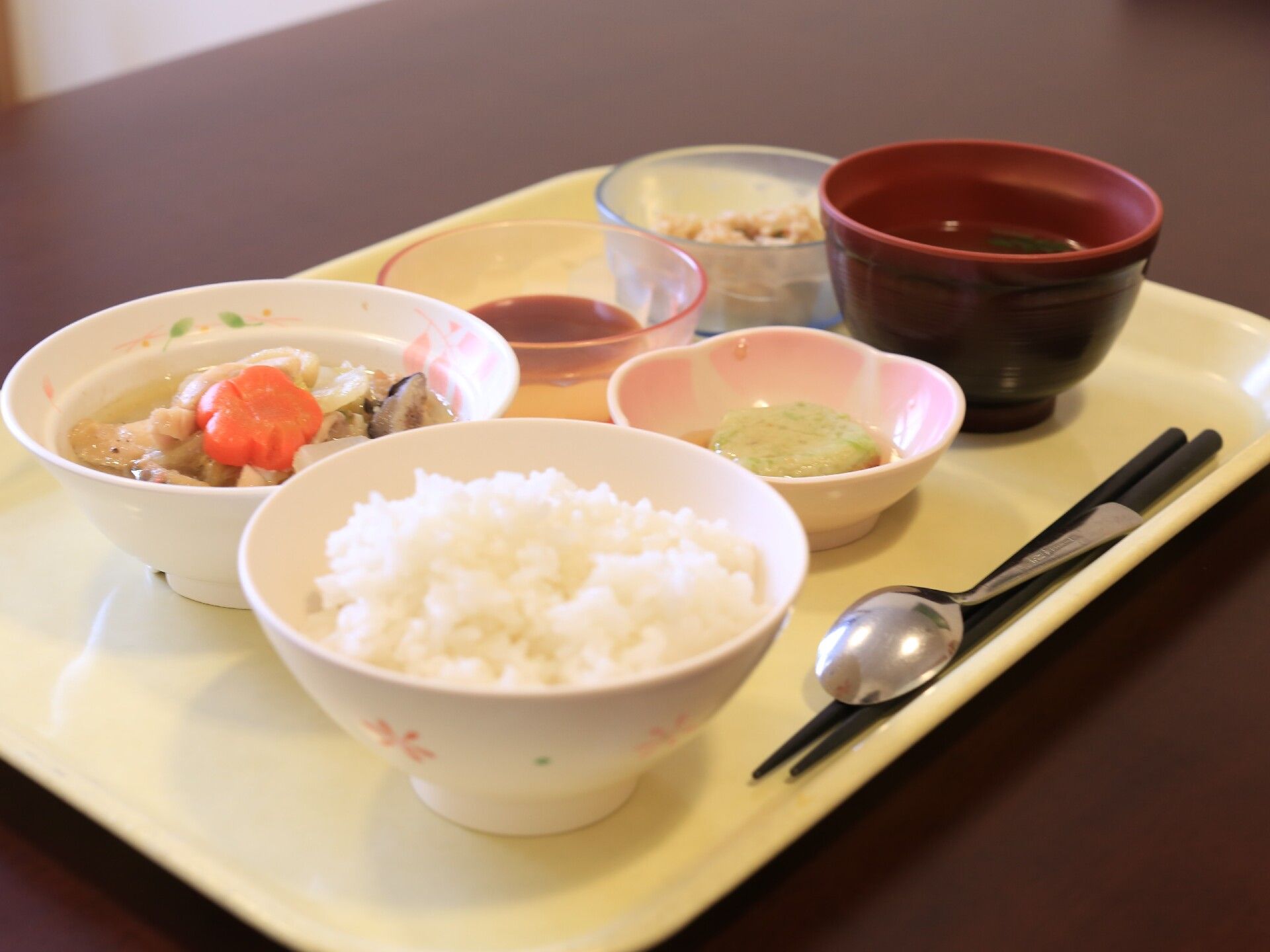 白いプラスチック製のお盆の上に、ご飯やおかずが並べられている食事一式