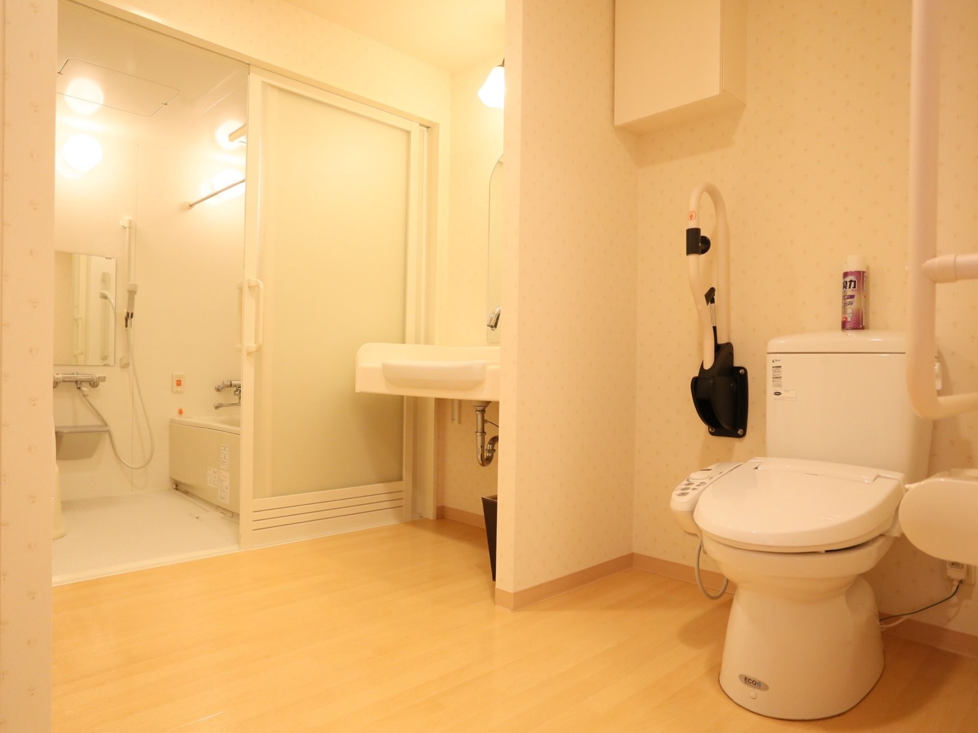 手すり付きと温水洗浄便座が設置されたトイレの奥に、洗面台がある。その奥の引き戸の中は浴室になっている。