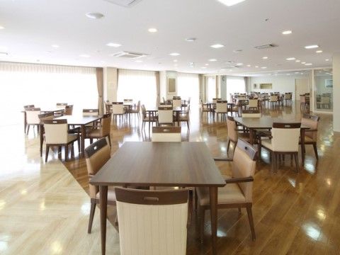 大きな窓があり、明るく広々とした部屋。窓に対し斜めに配置された茶色の４人掛けテーブルセットが、ゆとりのある間隔でたくさん並んでいる。