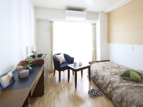 部屋にはベッドをはじめ、チェストや机、１人掛けソファーとテーブルも用意されている。木製の家具はこげ茶色で統一している。