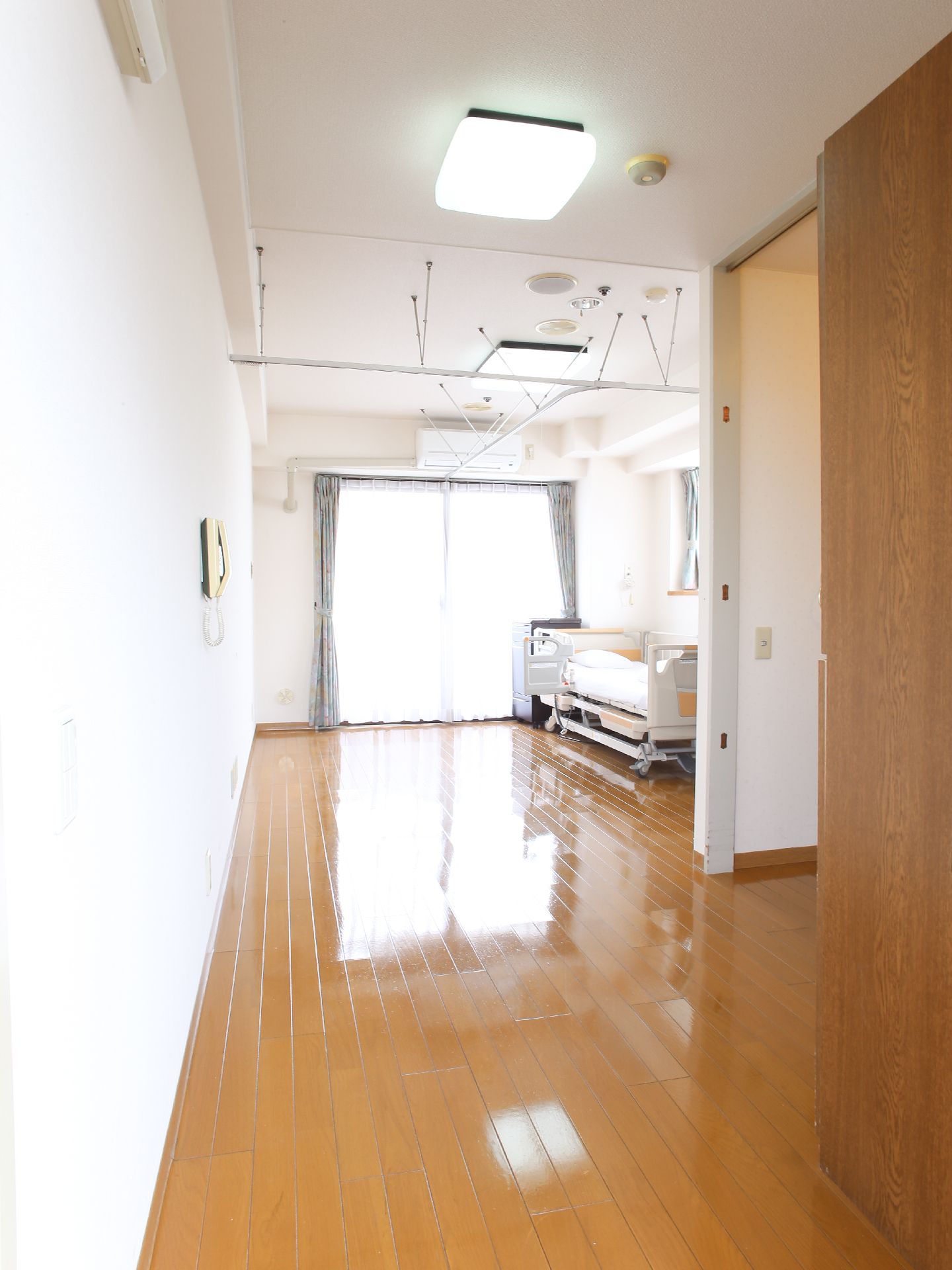フローリングの床はピカピカに磨かれて光っている。天井に室内の仕切用のレールカーテンのレールが渡されている。