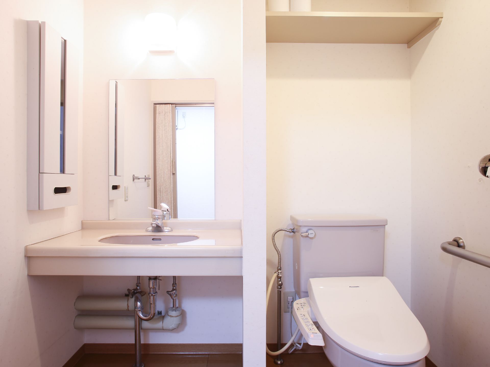 トイレ個室内に便座と流し台を用意している。右側に便座があり、温水洗浄便座が設置されている。流しの前の壁には鏡が取りつけられている。