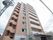 高層マンションのような外観で、１階に施設の入口があり、入口ドア前には屋根がついている。建物には外階段が設置されている。
