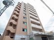 高層マンションのような外観で、１階に施設の入口があり、入口ドア前には屋根がついている。建物には外階段が設置されている。