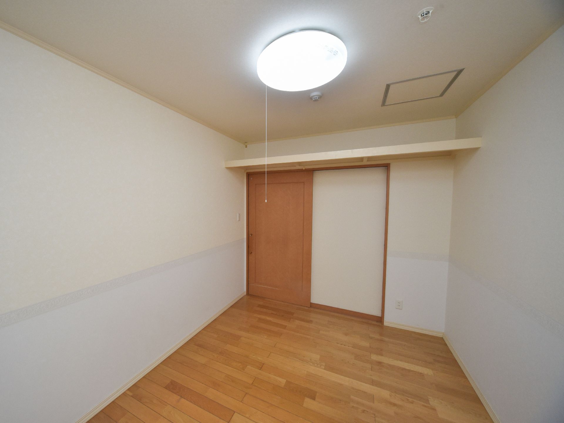 ドアと床は木で出来ている。ドアの上には収納棚が付いている。天井には照明と煙を感知する機械が設置されている。