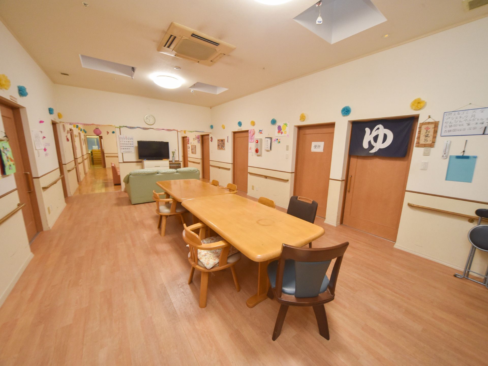 浴室の扉に「ゆ」の暖簾が掛かっている。隣はトイレになっている。壁には色々な飾りの他、非常ベルの設置がある。