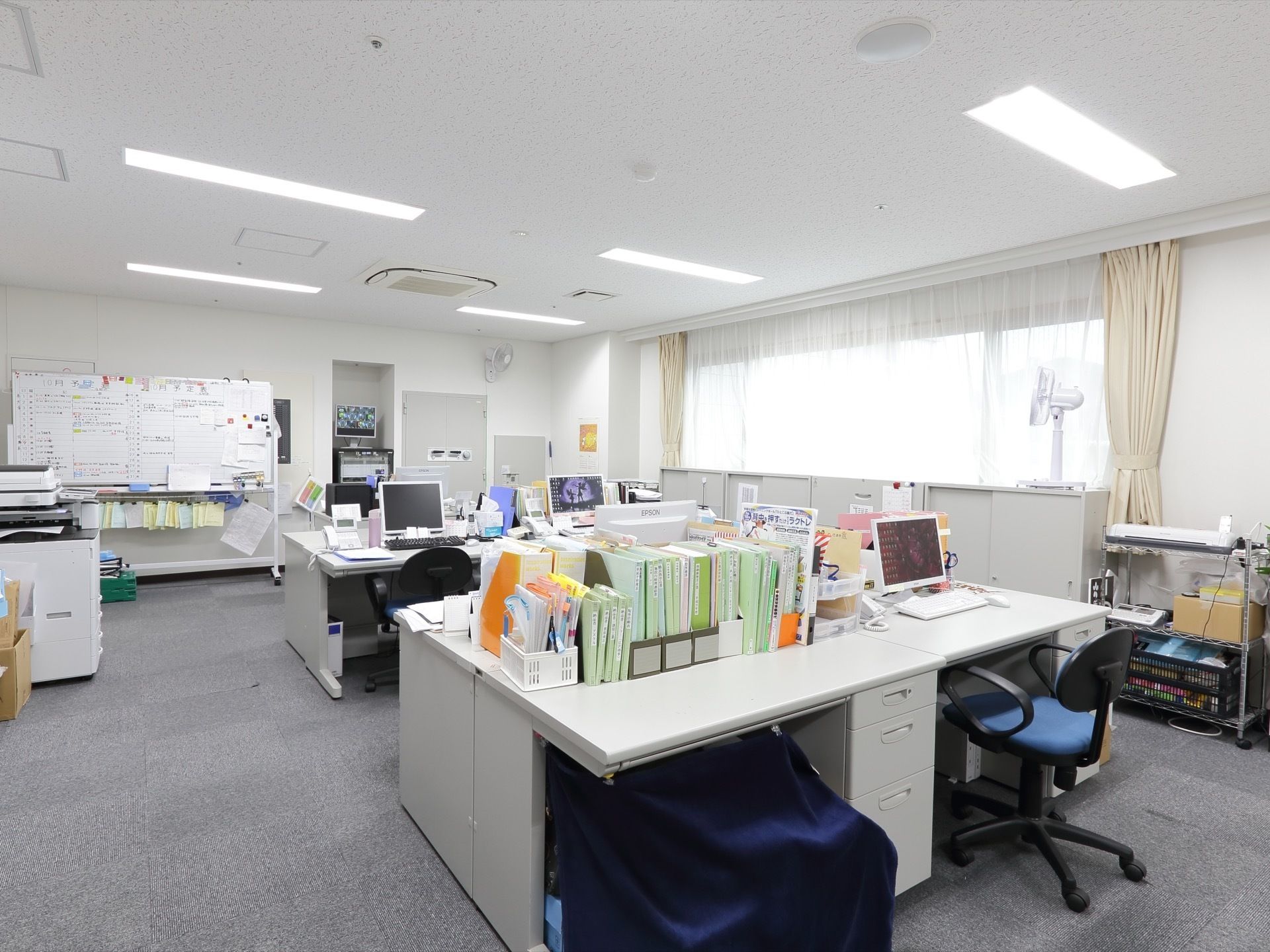 広い部屋となっているスタッフルームにはたくさんのデスクとイスがあり、デスクの上には様々な種類の書類が置かれている。