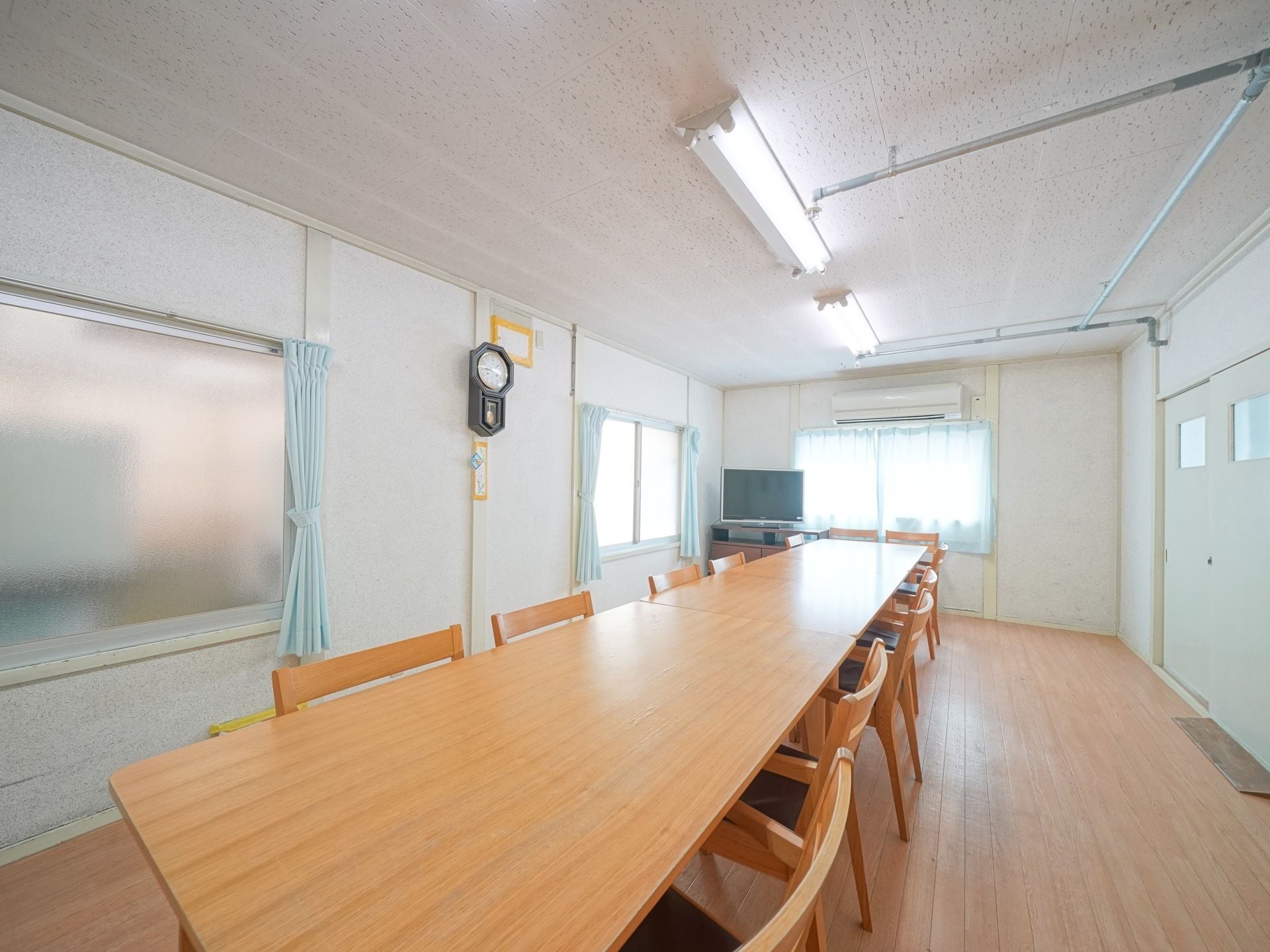 中央にテーブルを配置した座席があるレイアウトになっている。奥の窓際には大きなテレビとエアコンが設置されている。
