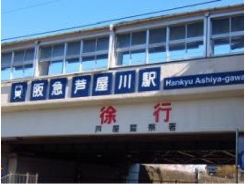 白い壁に青い駅名の看板が貼られ、赤い字で徐行と書かれた駅舎