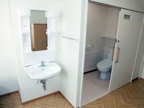 左に鏡付きの洗面スペース、右側に引き戸の付いたトイレがある水回り