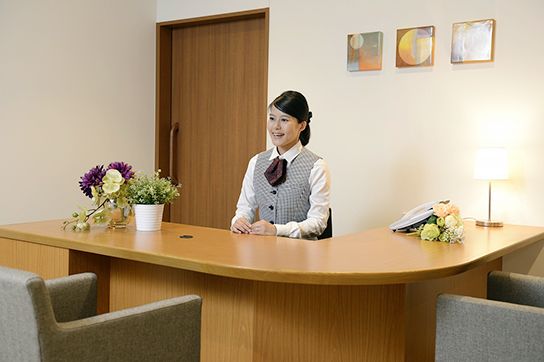 テーブルの奥には男性スタッフが座り、手前には高齢女性と女性の家族ら敷女性が座り、対面で話している。