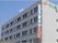 グレーを基調とした建物である。外壁上部には緑色で施設名とワンポイントが描かれており、縦長の看板が取り付けられている。