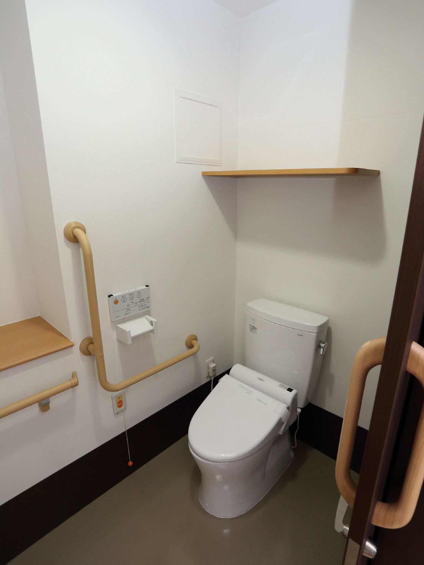 トイレは手すりがついていて、呼び出しボタンがあるので安心して利用できる。ウォシュレットのボタンが壁にあり、棚もついているので使いやすい。