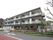 3階建ての建物は黒が基調となっていて鉄骨造になっている。各部屋のベランダ側が道路に面していて、エアコンの室外機が見えている。