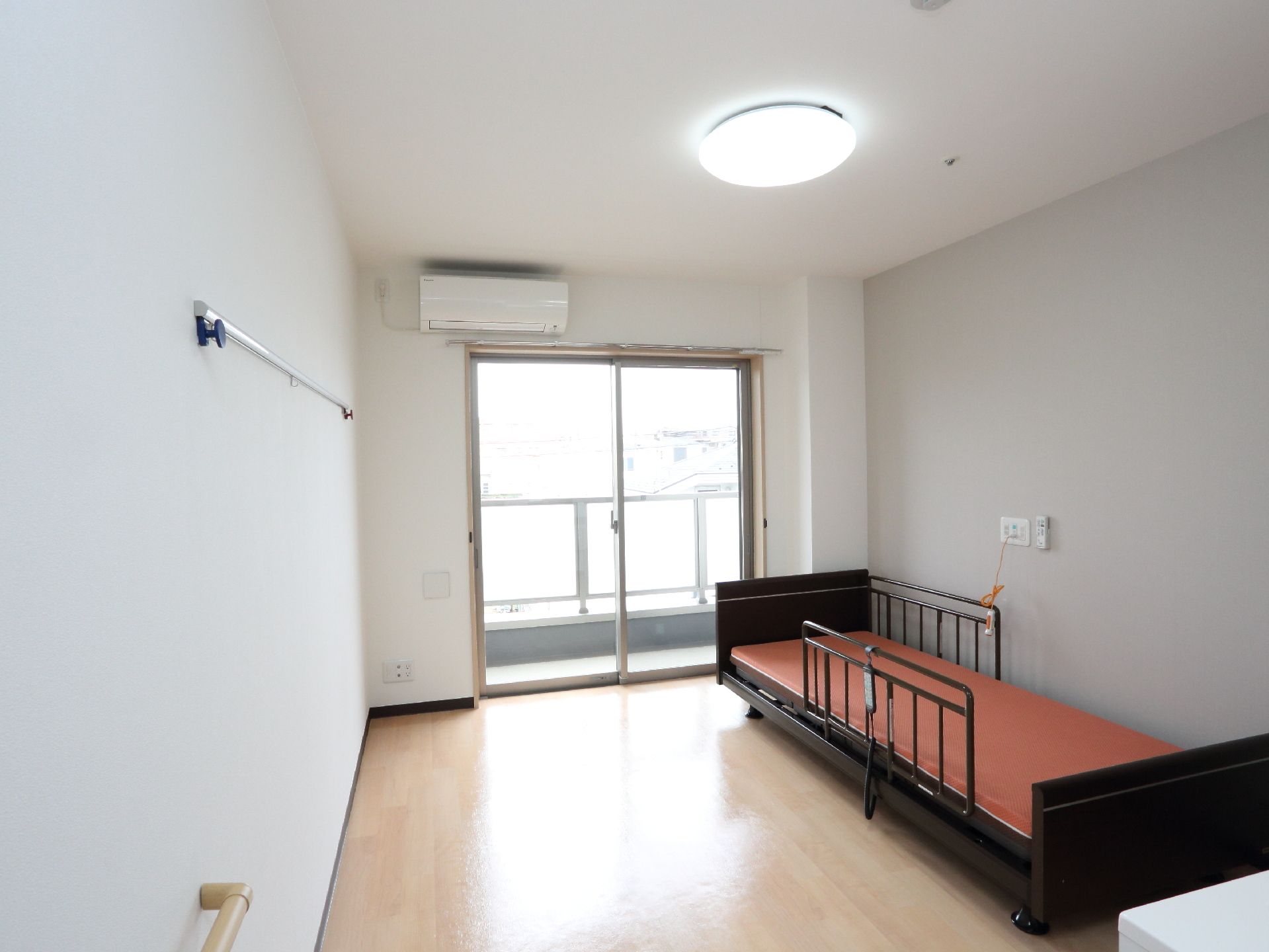 白い壁とベージュのフローリングで明るい部屋になっている。エアコンが設置されていて快適に過ごすことができる。