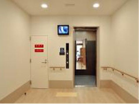車椅子でも利用できるエレベーター。床と巾木は白木で、天井と壁はアイボリーなのでホール全体が明るい印象である。