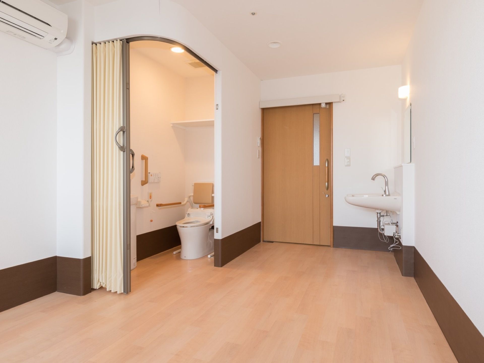 居室にトイレと洗面台を完備している。トイレには利用しやすいようにアコーディオンタイプのカーテンを設置している。