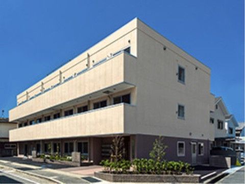 1階はブラウン、2、3階はベージュに塗られ、全面にベランダが配された外観の建物