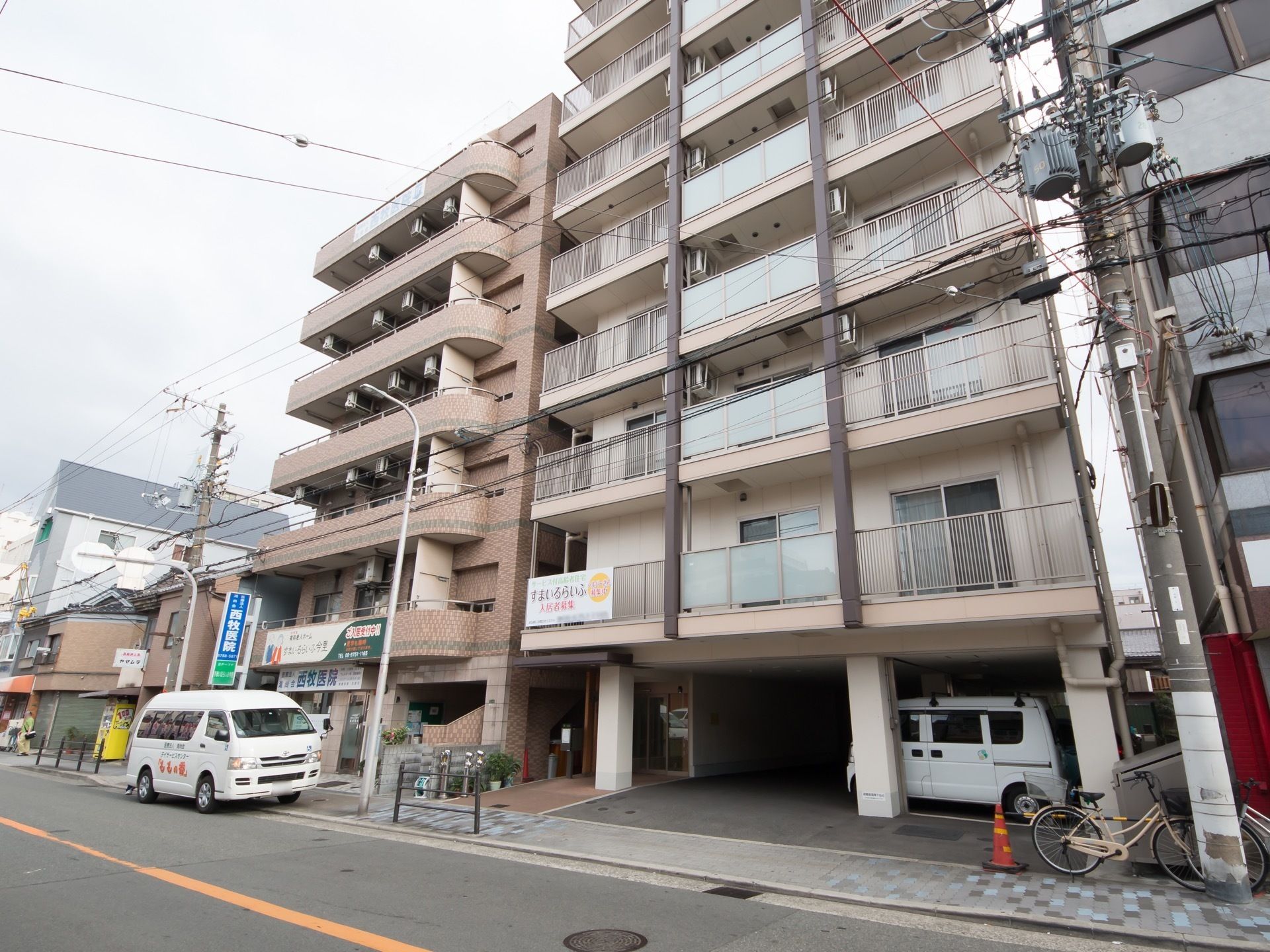 ８階建の鉄筋コンクリートの建物であり、１階部分は駐車スペースになっている。周囲には住宅や病院、お店などが立ち並んでいる。