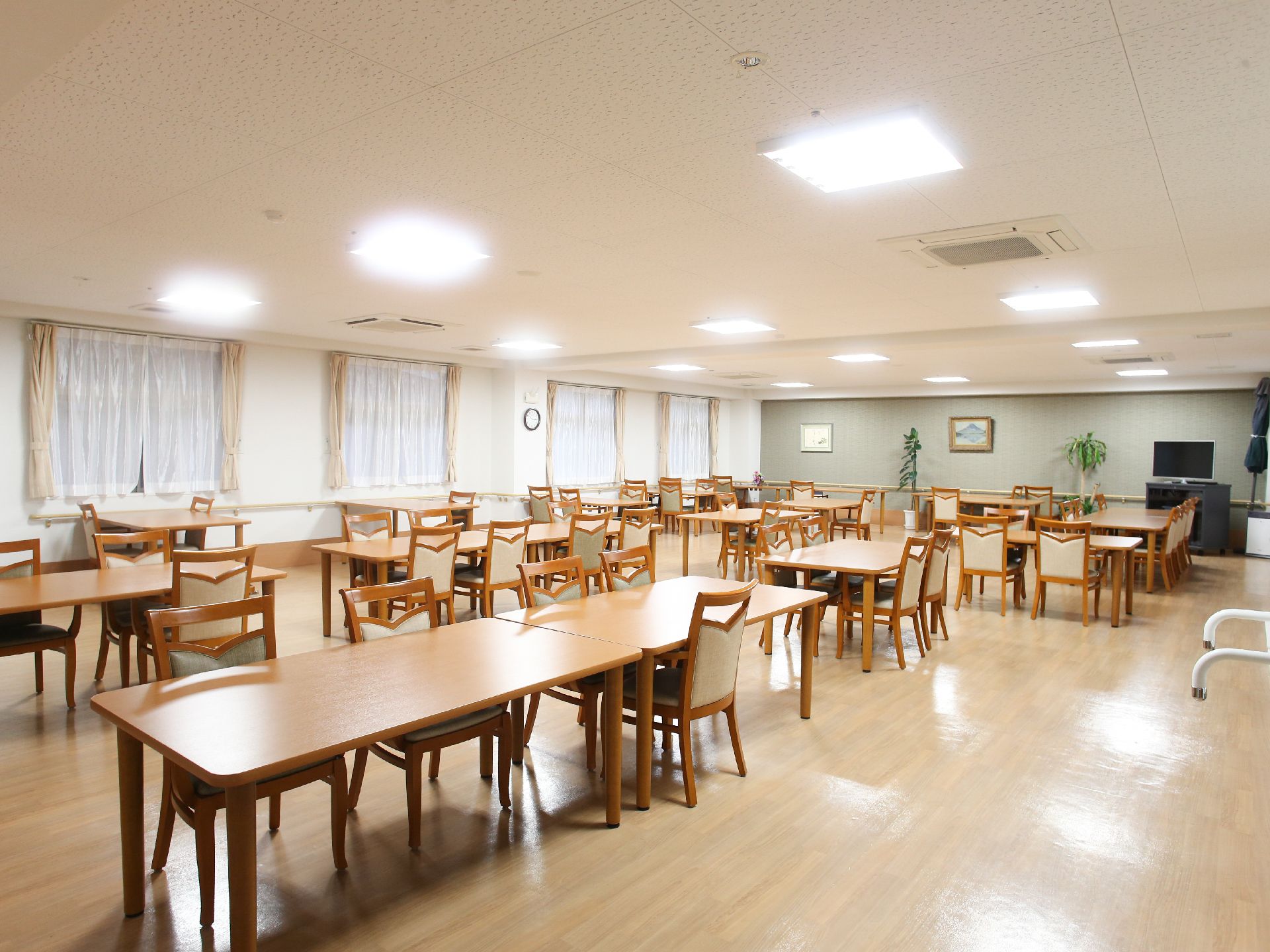 広々とした共用のダイニングルームには、イスやテーブルが置かれている。また入居者様がくつろげるように、テレビも用意されている。