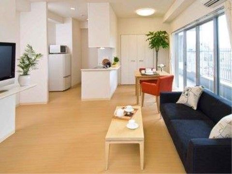 奥にカウンター付きのキッチンがあり、その右にブラウンのソファの置かれたスペース