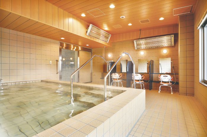 施設内に天然温泉を用意している。タイル貼りの大浴場は明るく清潔感がある。シャワーチェアが３脚置かれている。