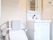 フラットなフロアにトイレと洗面台が並んでいる。トイレには両側に手すりがあり、背面に背当てパッドが設置されている。