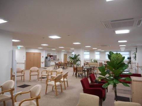手前右に観葉植物と応接セット、左側にはホワイトボードを囲むように椅子が半円状に並べられている。奥にはテーブルセットがいくつか置かれている。