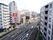 居室のベランダに出ると町の景色を一望できる。眼下には広い道路が通っており、両側にはビルや店舗が立ち並んでいる。