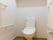 白色を基調とした明るいトイレである。両側の壁には安全性を考慮し手すりがあり、奥の壁には物置用の棚が設置されている。
