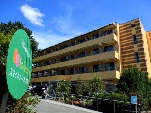 「スマイルコート茨木紫明園」の外観。緑色の施設看板が目印であり、4階建てのマンションチックなデザインである。