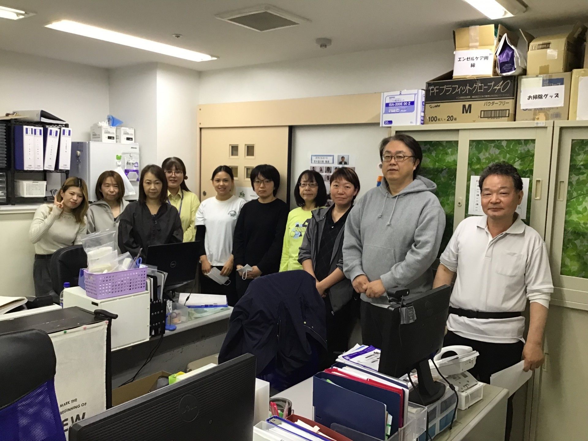 色紙の輪で飾られた食堂に、前列に屈んでいる3人、後列に6人が並ぶ集合写真