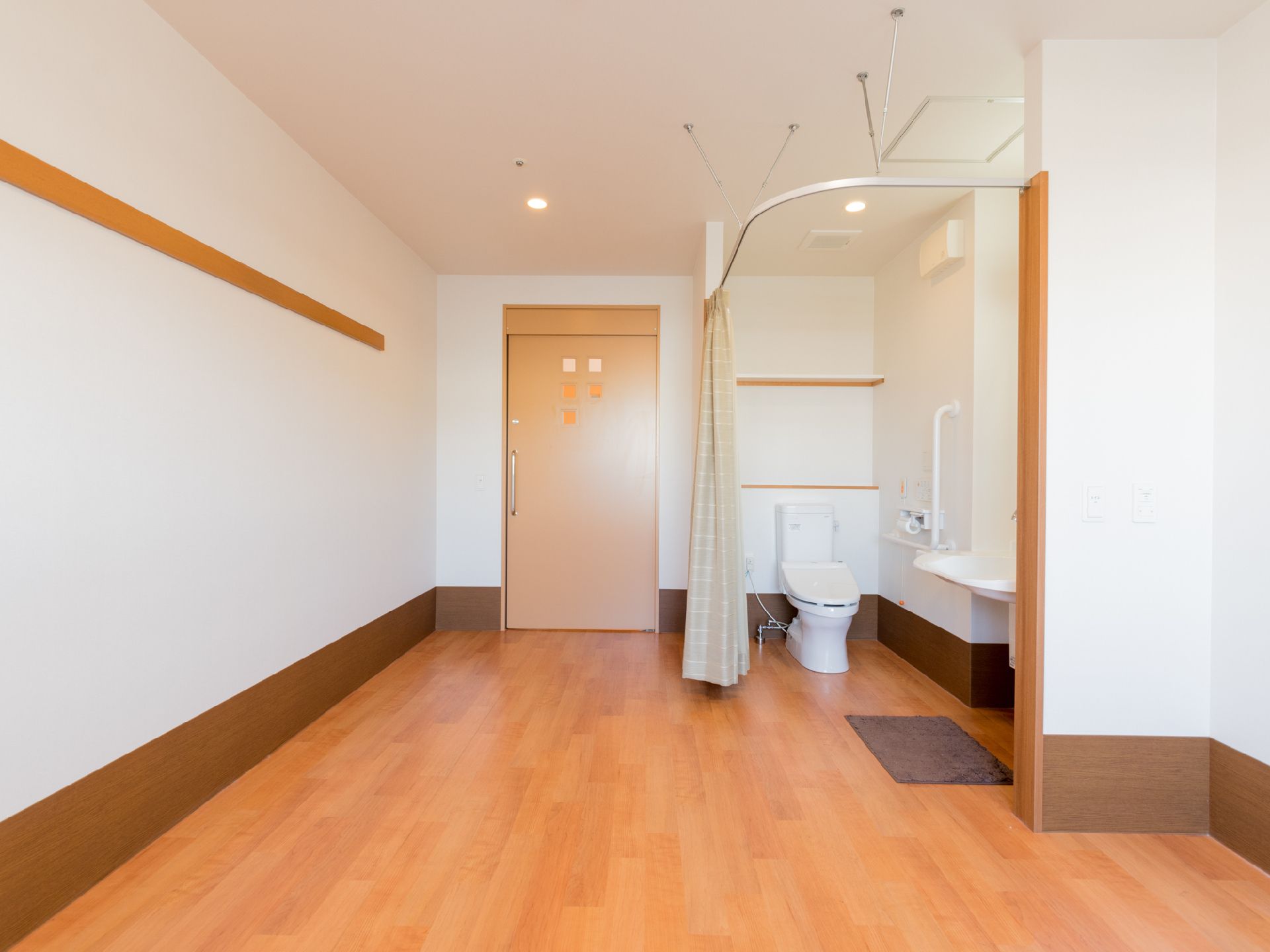 居室は十分な広さがあり、カーテンで間を仕切ったトイレと洗面所が完備されている。入り口のドアは開閉が楽な引き戸になっている。
