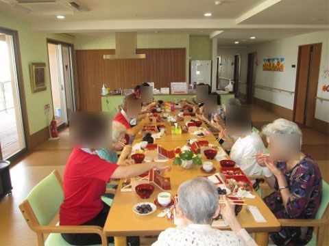 左側に窓のある食堂で、テーブルについて食事をしている10人ほどの人物