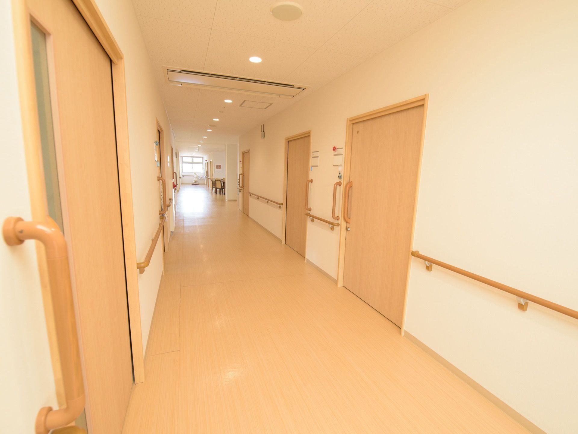 通路の両側に手すりが取りつけられ、居室のドアは引き戸式になっている。奥に窓があり、十分な採光がある。
