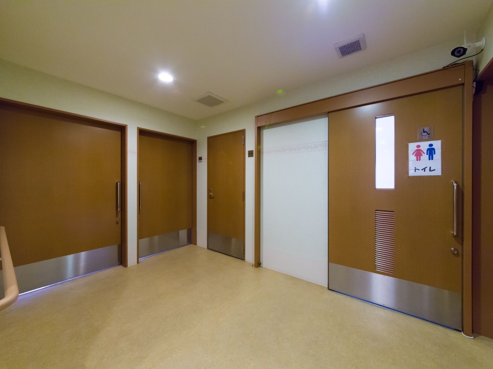 広々とした廊下のつきあたりには共有トイレがある。大きな取っ手が付いた引き戸タイプの扉である。大きな文字でトイレと書かれている。