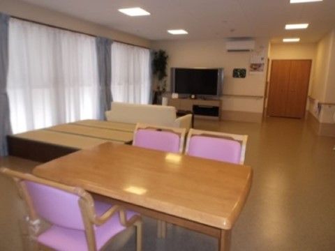 左に窓がありその手前に畳スペース、さらに手前にテーブルと椅子がある共用スペース