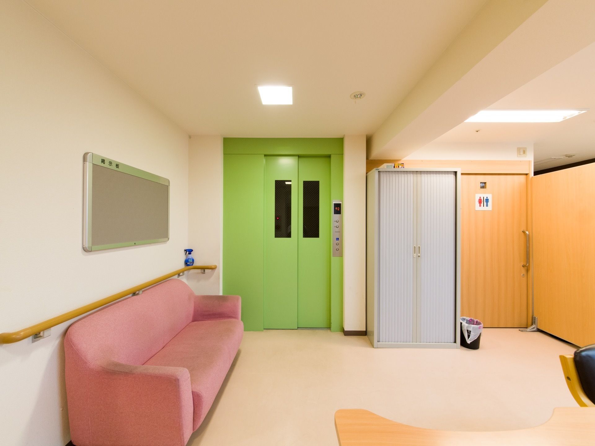 エレベーター前にはピンクの３人掛け用のソファが置かれている。共有のトイレもあり、わかり易く表記されている。