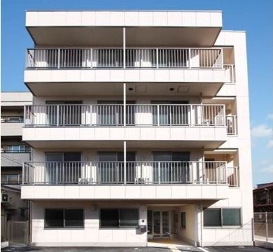 1階に玄関、2階から4階に居室のベランダが伸びる白い外観の建物
