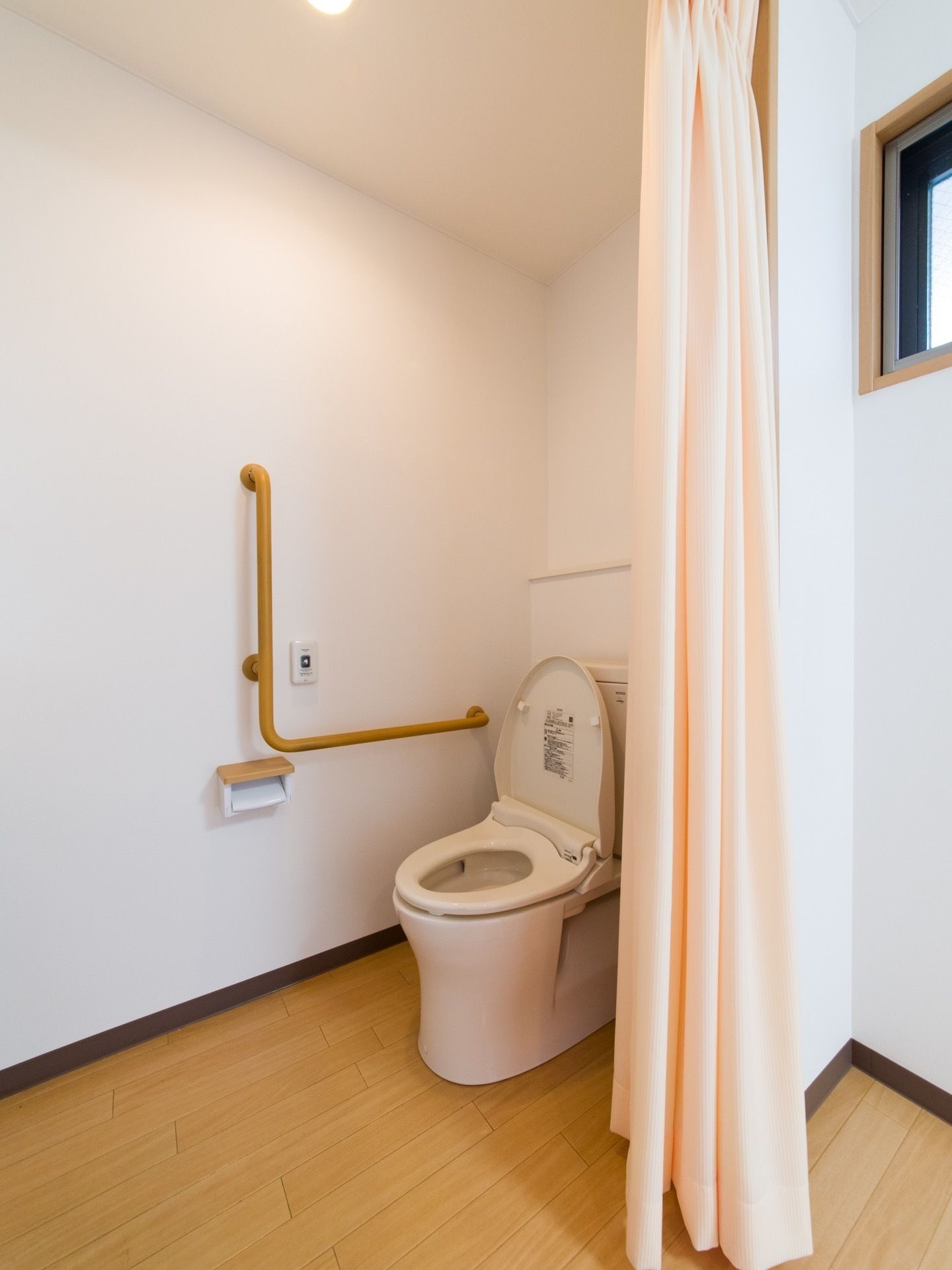 居室のトイレの扉はなく、カーテンで仕切っている。ドアの開け閉めがなく、車いすでの利用も容易に行える。