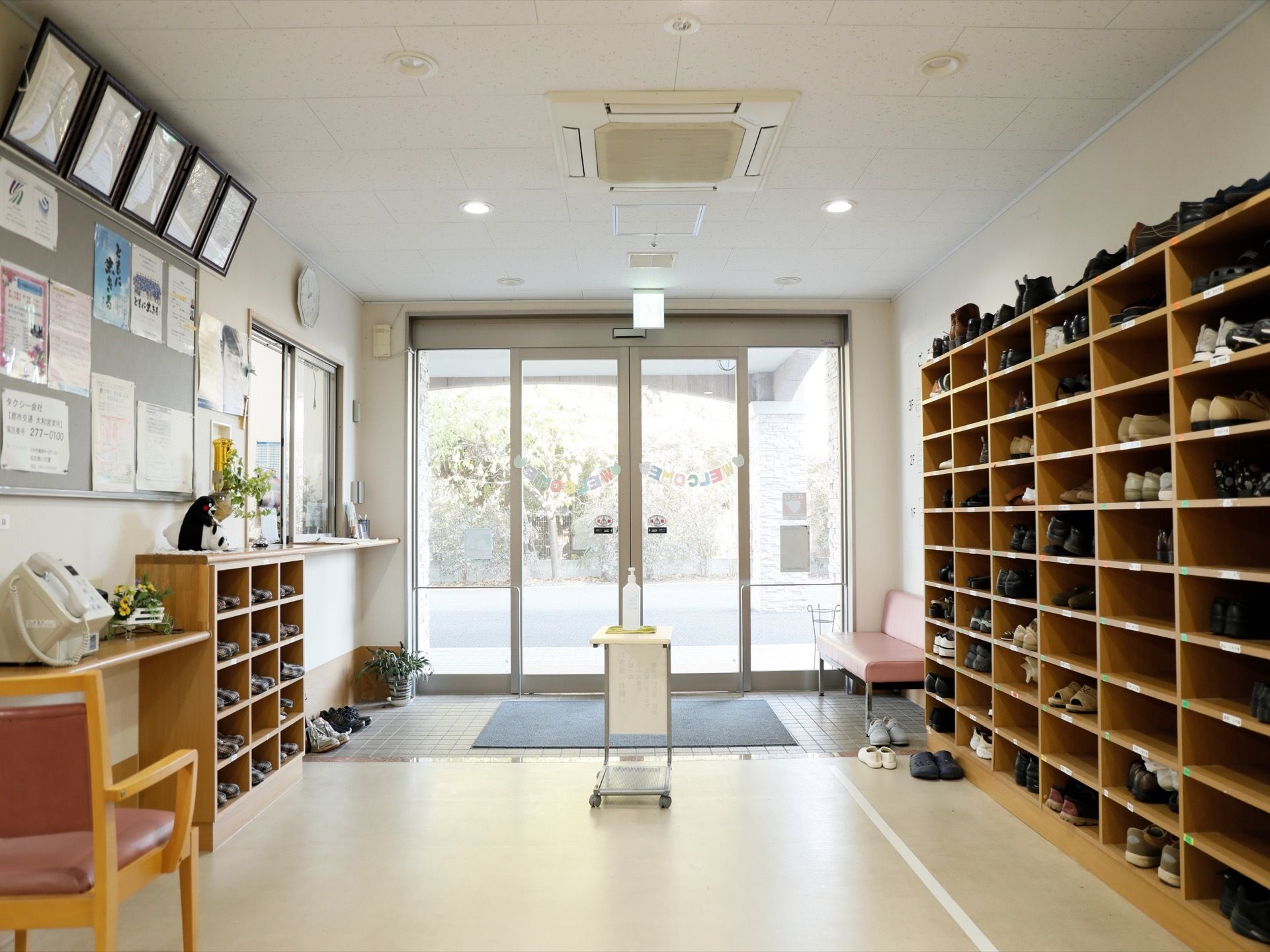 明るく広い玄関ホールで、透明の自動ドアになっている。入って左手には入居者様のシューズボックス、右手には来客用スリッパが置かれている。