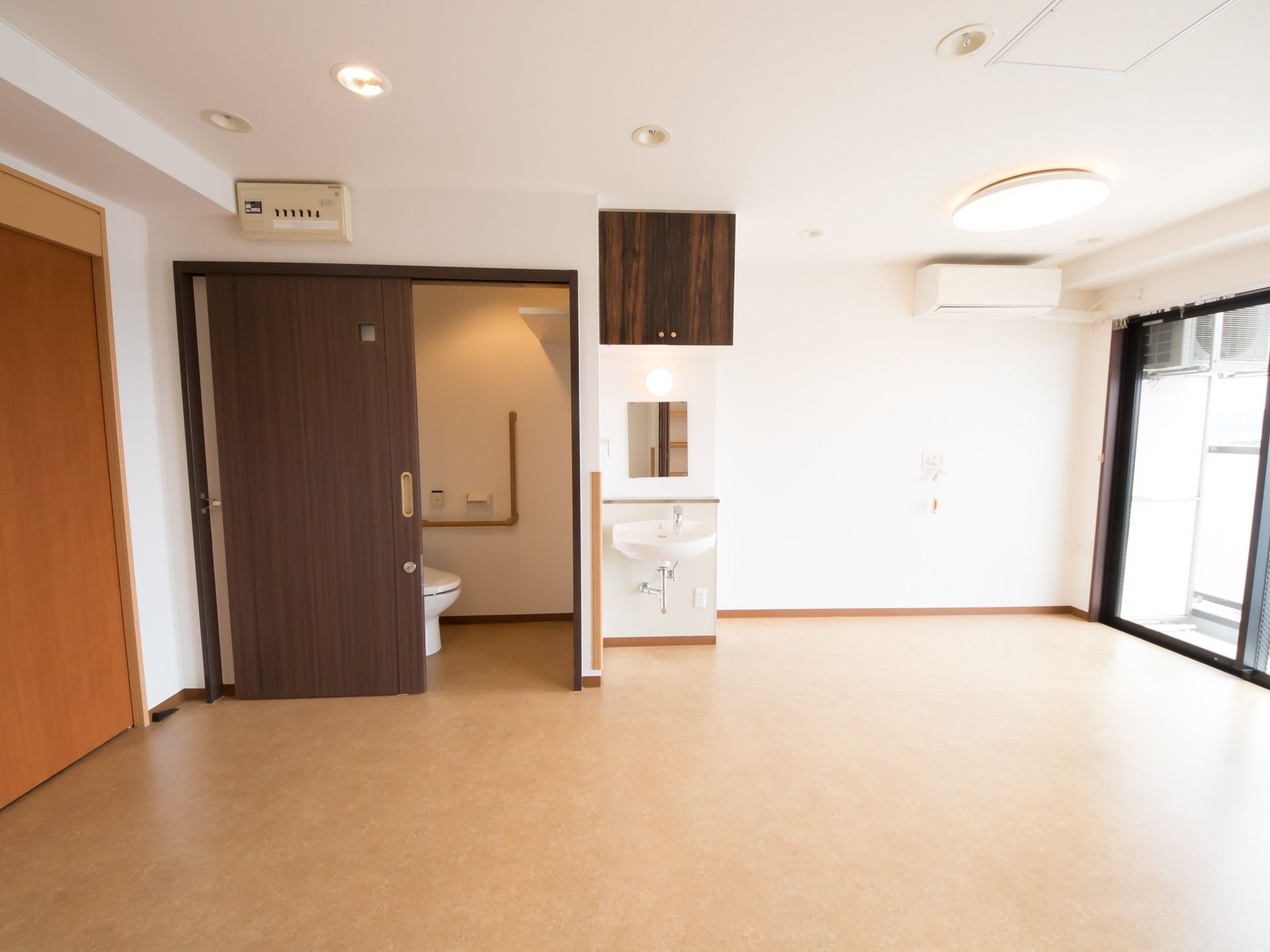 大きな窓から太陽光が差し込む大きなお部屋。トイレのドアは高級感を感じる。空調や照明も申し分なく、快適に過ごせるつくりである。